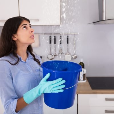 woman-holding-bucket-because-roof-is-leaking